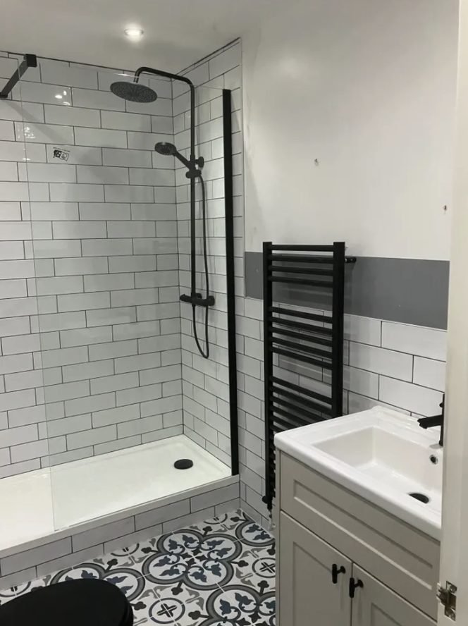 Shower room with white metro tiles, black towel rail and patterned floor tiles